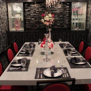 A beautifully set dining room with a modern and elegant ambiance, featuring red chairs and a floral centerpiece.