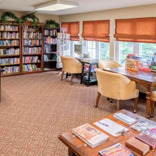 A cozy library room with bookshelves, tables, and chairs for reading.