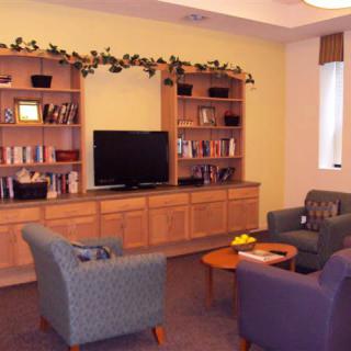 A cozy living room with bookshelves, a television, and comfortable seating.
