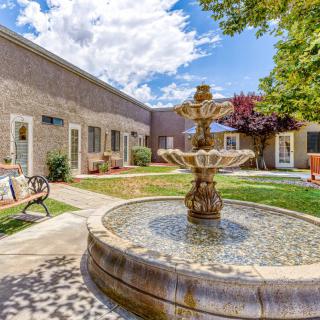 A serene courtyard with a central fountain surrounded by a well-maintained garden and seating areas.
