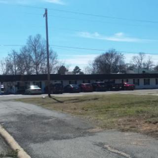 A view of a motel with parked cars and a clear blue sky in the background.