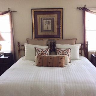 A cozy and well-appointed bedroom featuring a neatly made bed with decorative pillows and framed artwork above.