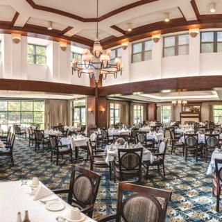 Spacious dining room with elegant decor, featuring multiple tables and a large chandelier.