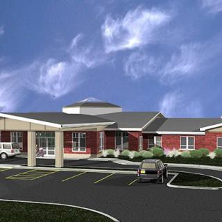A modern hospital building with a parking area under a clear blue sky.
