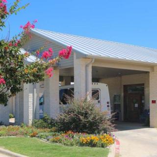 A building entrance with a covered awning and colorful landscaping.