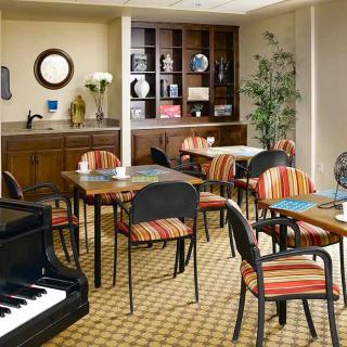 A cozy cafe interior with tables, chairs, a piano, and decorative elements.