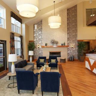 A modern living room with a high ceiling, featuring stylish furniture and a central fireplace.