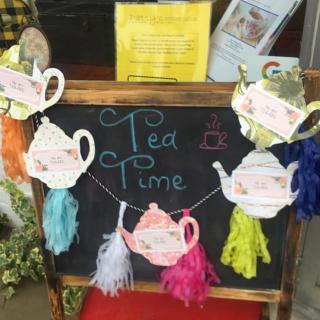 A decorative chalkboard sign with colorful teapot and feather garlands, indicating 'Tea Time'.