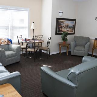 A cozy living room with armchairs, a dining table, and a painting on the wall.