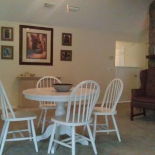 A cozy dining area featuring a white round table with matching chairs, adorned with wall art and decor.