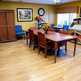 A cozy dining room with a wooden table and chairs, featuring colorful decor and a large cabinet.