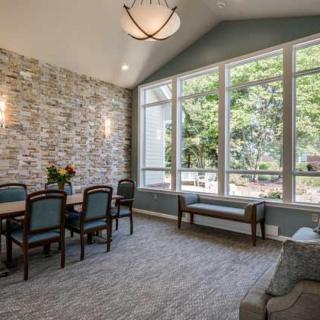 A cozy dining area with large windows and a stone accent wall, allowing natural light to fill the space.