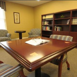 A small office meeting room with a wooden table, chairs, and a bookshelf.