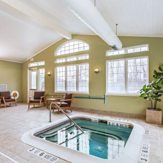 A cozy indoor spa facility with a jacuzzi and comfortable seating, illuminated by natural light from large windows.