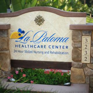 Sign for La Paloma Healthcare Center offering 24-hour skilled nursing and rehabilitation services.