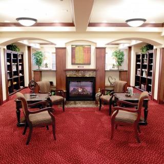 A cozy library setting with a fireplace, surrounded by bookshelves and seating arrangements.