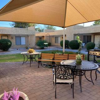 A charming courtyard patio with tables, chairs, and a shade sail providing a relaxing outdoor space.