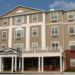 A multi-story residential building with a porch and several windows.