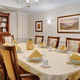 A well-decorated dining room with a long table set for a formal meal.
