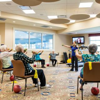 A group of seniors participating in an indoor exercise class at a retirement community.
