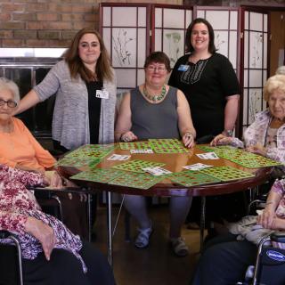 A group of women gathered around a table playing cards.