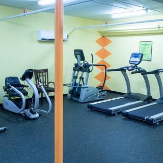 A small gym room equipped with treadmills, a stationary bike, and an elliptical machine.