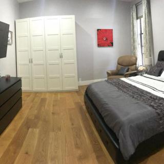 Modern bedroom with a large bed, wardrobe, and wooden flooring.