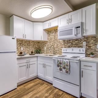 A modern kitchen featuring sleek white cabinetry and stylish stone backsplash.