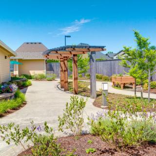 A beautifully landscaped garden with a pathway, wooden pergola, and bench.