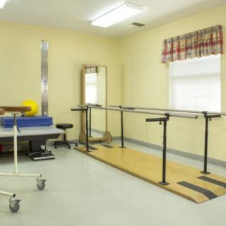 A rehabilitation room equipped with parallel bars and other physical therapy tools.