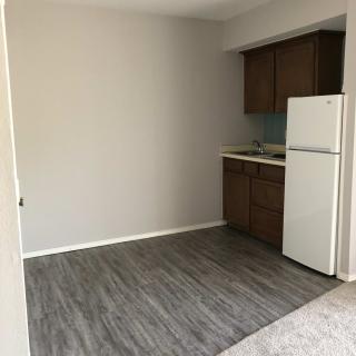 Empty kitchen space in an apartment with wooden cabinets and a gray floor.