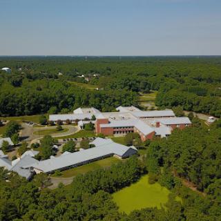 A bird's-eye view of an educational facility surrounded by lush greenery.