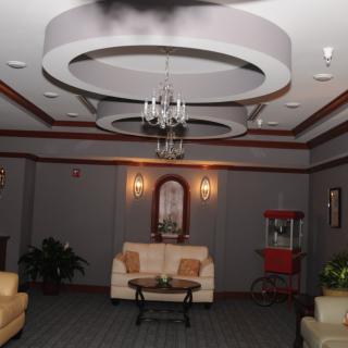 A cozy living room with elegant chandeliers, comfortable sofas, and a nostalgic popcorn machine in the corner.