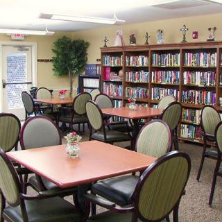 A cozy library reading area with shelves full of books and several tables and chairs for visitors.