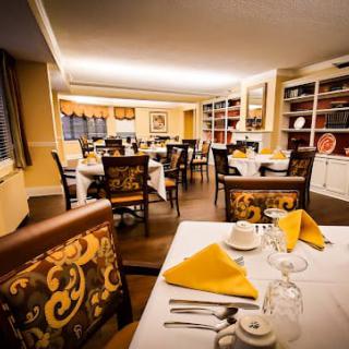 A cozy restaurant dining room with elegantly set tables and warm lighting.