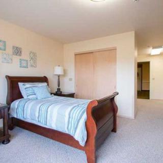 A cozy bedroom with a wooden single bed and striped bedding, complemented by a nightstand and lamp.