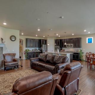 A spacious open-concept living area featuring a modern kitchen, comfortable leather seating, and a dining space on hardwood floors.