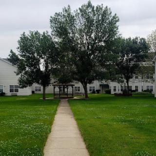 A peaceful view of an apartment complex surrounded by greenery and a walking path.