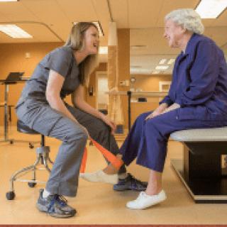 A healthcare professional assists an elderly patient during a physical therapy session.