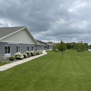 A building with a neatly maintained lawn and pathway under a cloudy sky.