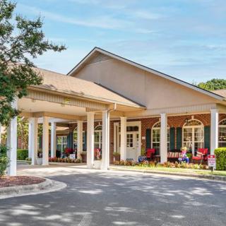 A welcoming entrance to a residential building with white columns and outdoor seating.