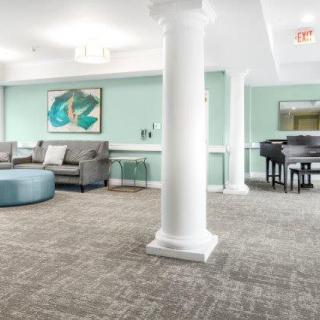 A modern lounge area with comfortable seating, a piano, and artwork on the walls.