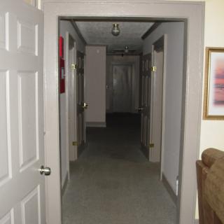 A view of a narrow hallway with doors on both sides.