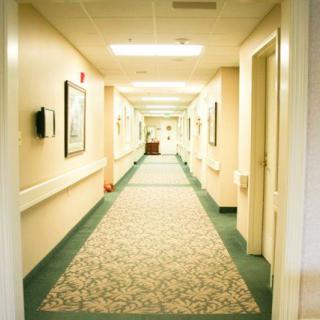 A well-lit hallway with carpeted flooring and multiple doors on either side.