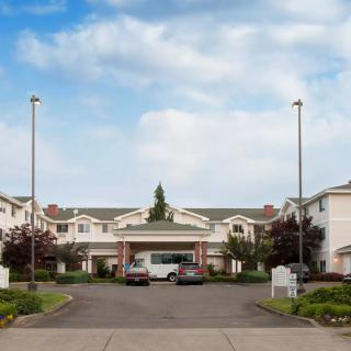 A residential building with a driveway and parked cars on a clear day.