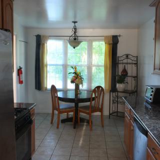 A cozy kitchen with a dining area featuring a small round table and chairs near a large window.