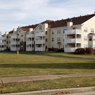 A view of residential apartment buildings with balconies, situated on a well-maintained lawn.
