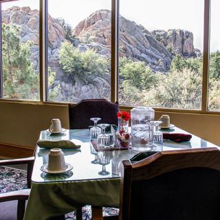 A dining table set near large windows with a scenic mountain view.