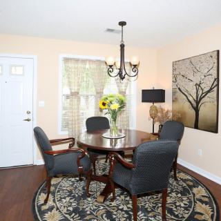 A cozy dining room with a round table, surrounded by chairs and decorated with sunflowers in a vase, under a stylish chandelier.