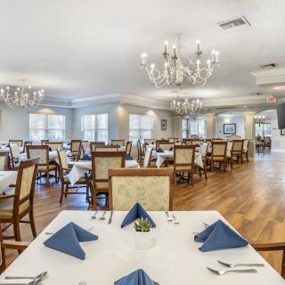 An elegant dining room with neatly arranged tables and chandeliers.
